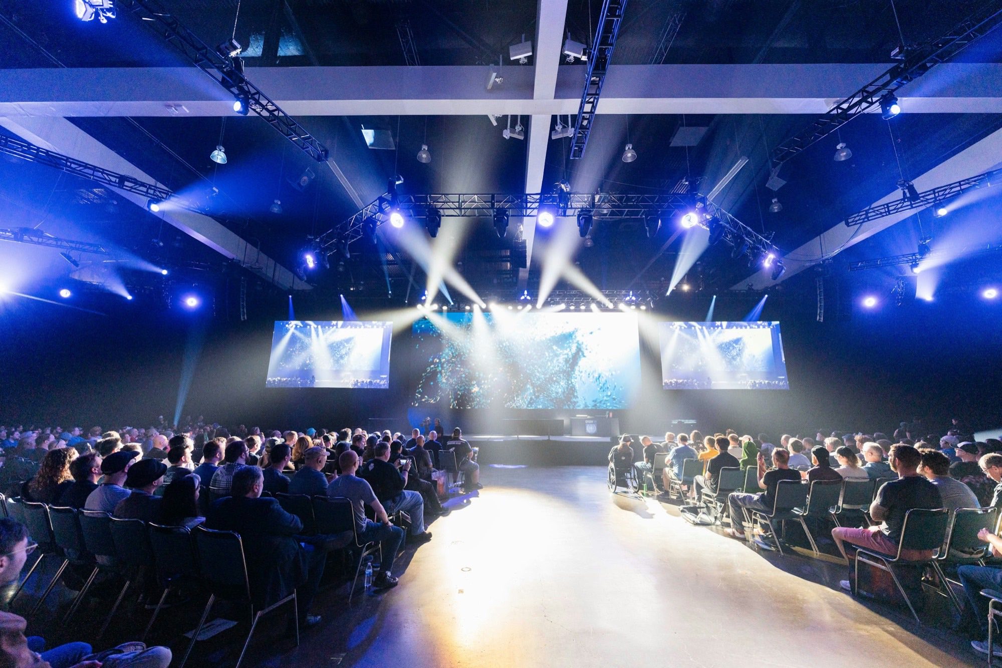 A full conference hall facing a lit stage
